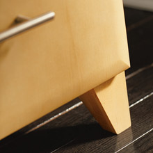 Close up of light wood cabinet with tapered leg