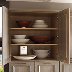 A frameless cabinet open with bowls on shelves